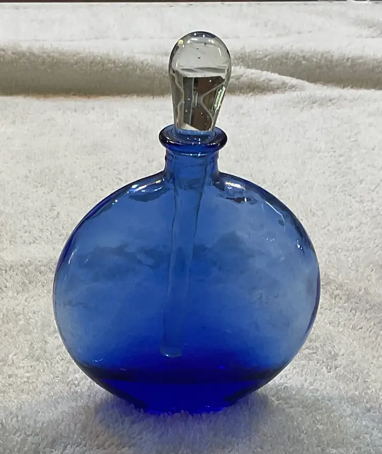 #01 Blue perfume bottle 6.5” tall with stopper and 4.5” wide and 1.5” deep. No chips or cracks on stopper or rim. Glass has a slight texture to it which adds sparkle
