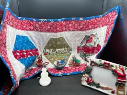 Vignette #10 Includes A Set Of 3 Vintage Bradford Exchange Charming Tails Ornaments. Anthropomorphic Mice In Teacups
The Essence Of Christmas By Dean Griff, A Winter Theme Picture Frame For A 3”x5” Photo, A Handmade Winter Theme Quilted Table Runner 16 1/2” X 33” Double Sided, And A Made By Me Acrylic Pour Painted Wooden Snowman Ornament Sealed With Resin.