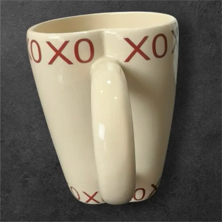 Cream Colored Ceramic Heart Shaped Coffee Mug With Red X’s and O’s Trim on the Top And Bottom