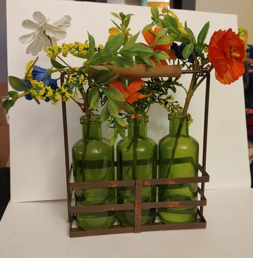 3 glass vases in metal holder with fake flowers. 8 inches high.