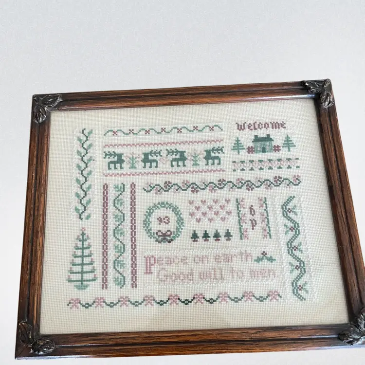 Framed Christmas cross-stitch sampler with holiday motifs and text.
Frame 9 1/2 x 11 .25 inches