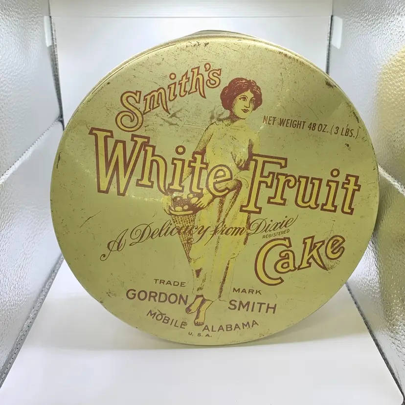 Smith’s White Fruit Cake Tin, A Delicacy from Dixie, Gordon Smith Bakery, Mobile, Ala, 8 1/4” x 3 1/4”.