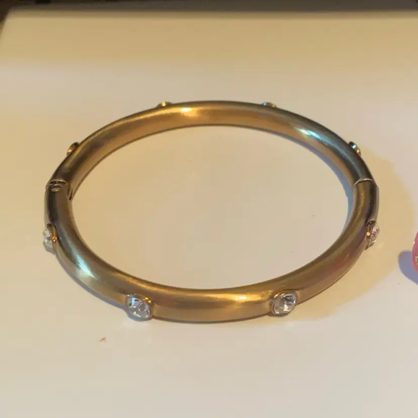 gold-toned hinged bangle bracelet with round clear Rhinestone stones.
