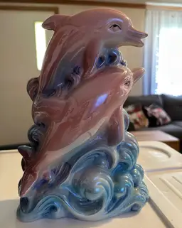 Porcelain figurine of dolphins leaping through waves.