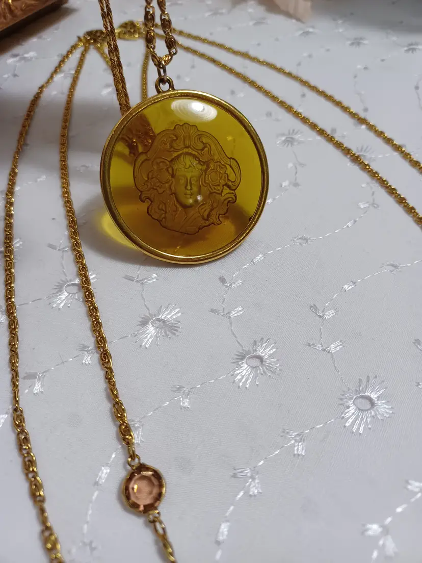 Vintage Goldette necklace has an amber colored acrylic pendant of Medusa framed in gold tone metal with fold over clasp