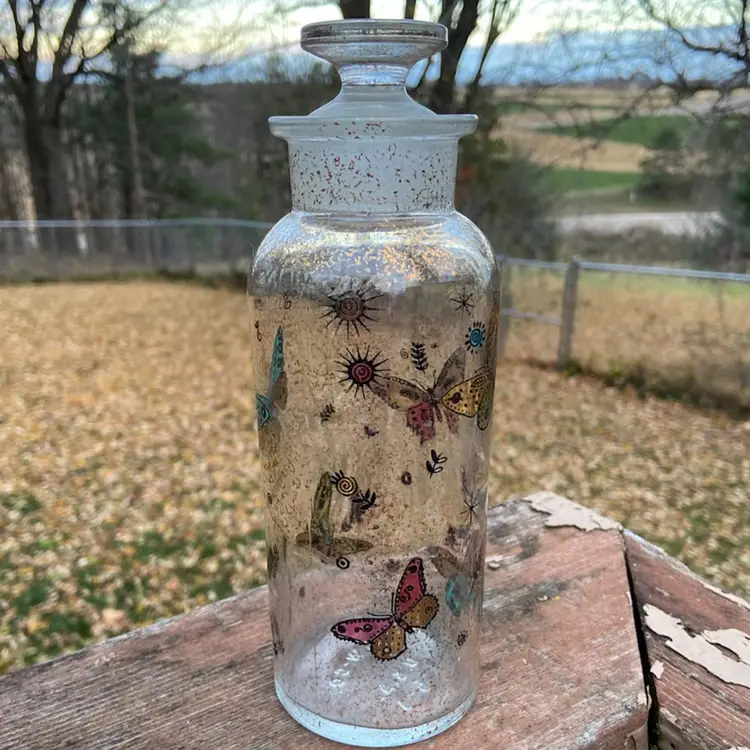 Georges Briard, Glass Apothecary Decanter / Glass Bottle With Stopper. Colorful Butterflies: Blue, Green, Red/Pink And Gold-toned Foiled Butterflies, with Foliage, Sun, And Stars Motif. 8.5”h.