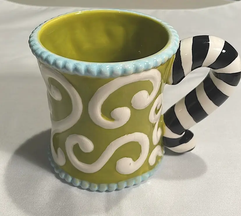 Mud Pie mug, green/off-white/lt. blue/black, “Cheshire Cat” tail handle