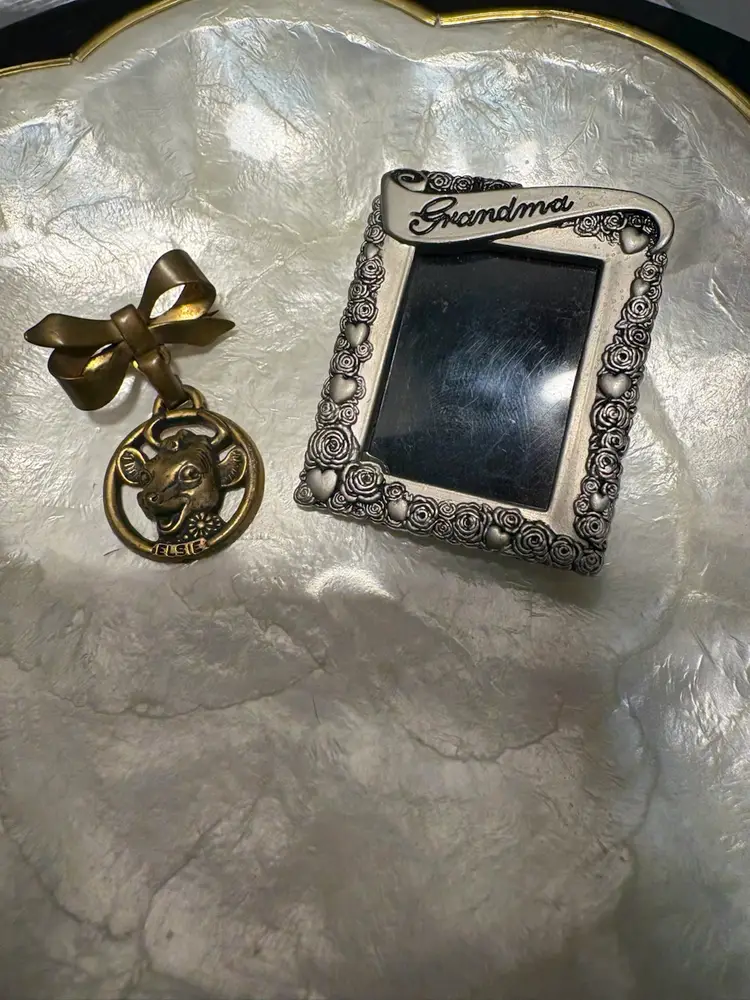 Vintage brass Elsie the Cow bow brooch and a silver-toned "Grandma" photo frame with rose and heart motifs Brock / Stand