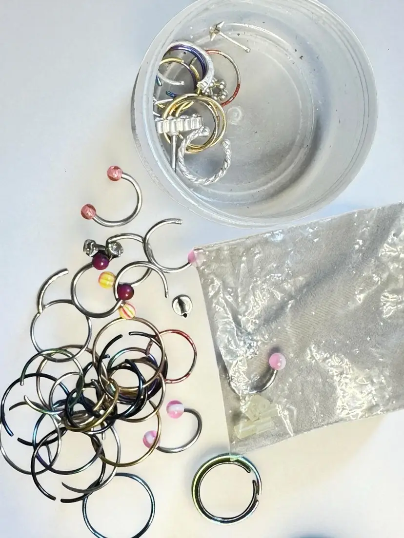 Small Plastic Jar with A Lot Of Body Piercings Jewelry