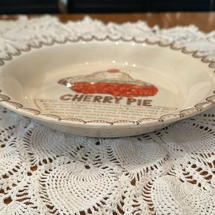 The Vintage Cherry Pie Plate Baking Dish is a charming addition to any kitchen collection, featuring a round ceramic piece with a colorful cherry pie design. This unique pie dish includes a cherry pie recipe, with its 10 1/4”diameter and 1.5" depth, this original piece from the 1980s is A Great nostalgic piece.  There is some crazing and a Small chip on the back shown in pictures.
