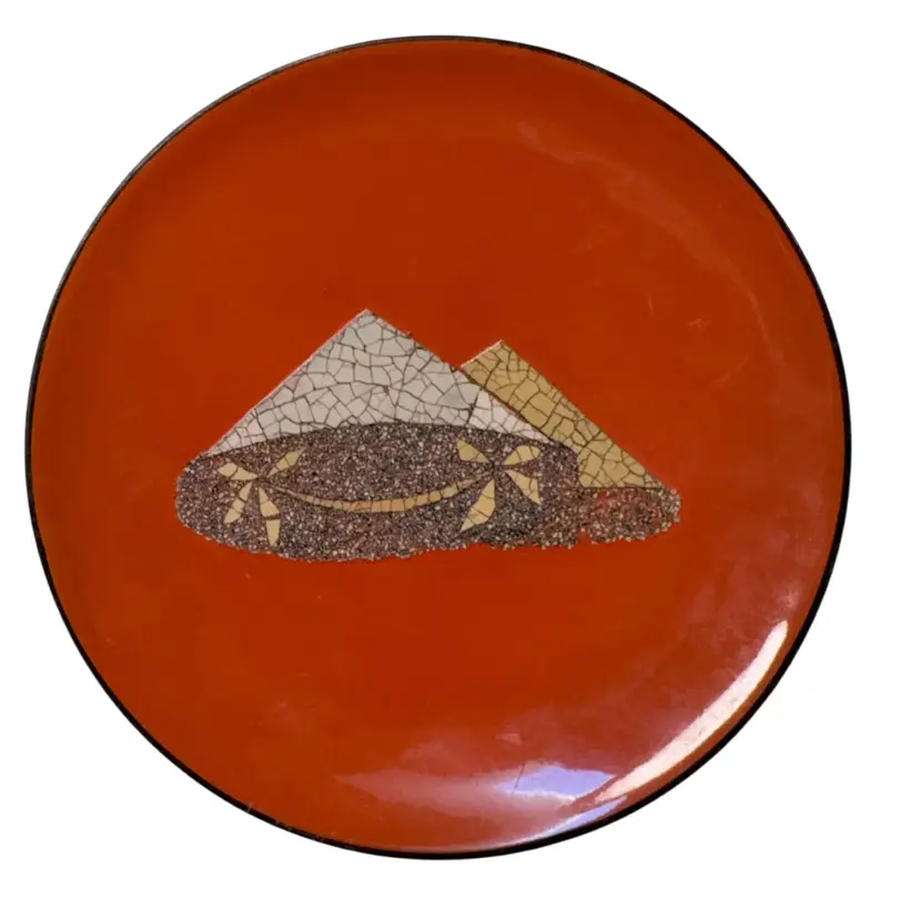MCM Style Japanese lacquered Dish featuring a mosaic-like design of conical hats (likely kasa) or stylized mountains set against a rustic orange background. 5” Round