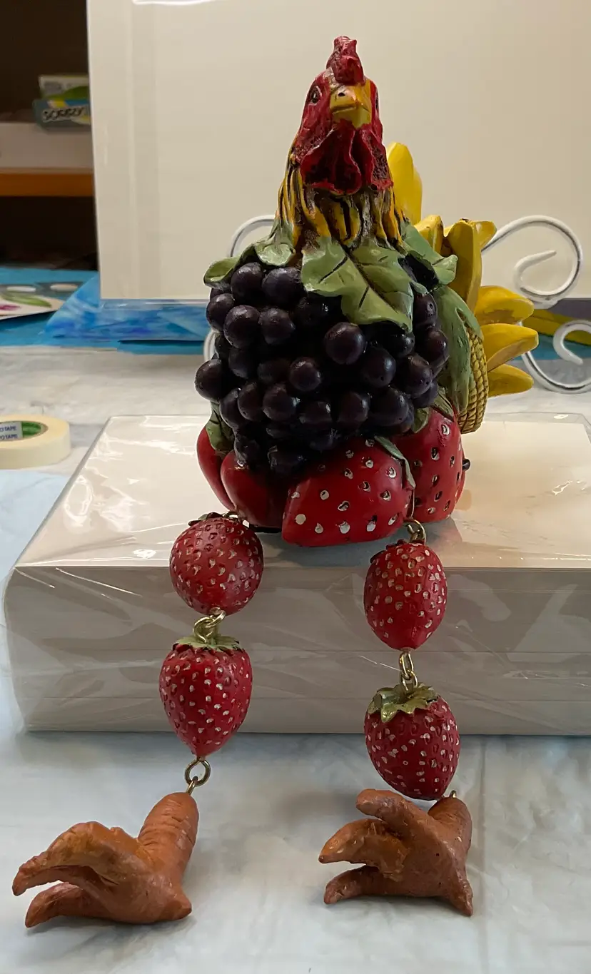 Resin Rooster in multicolored fruit, hinged dangling feet, 6” sitting, 10” comb to toes, 3 1/2” wide and 7” front to back