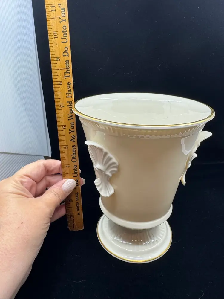 A cream-colored Lenox ceramic vase with shell motifs and gold trim