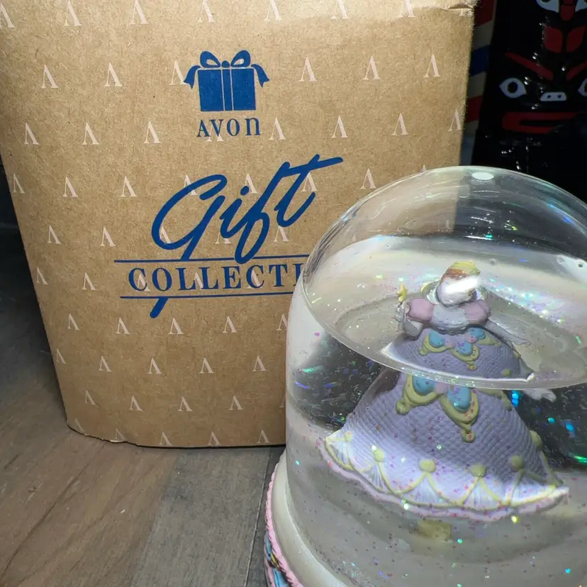 This is a decorative Musical Avon Fairy Queen snow globe with a princess figurine. Works In Original Box Plays “Swan Lake”