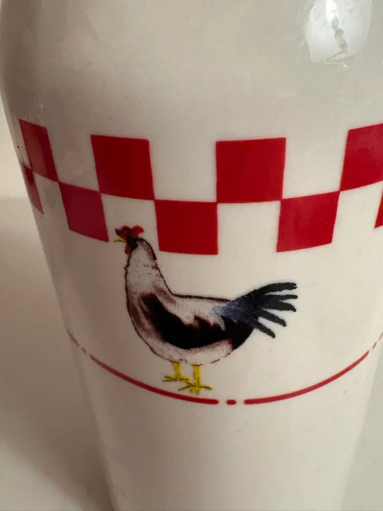 Ceramic milk jug or bottle with a rooster design and a red checkered pattern.