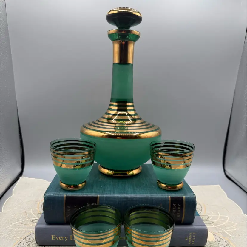 Mid-Century Modern "genie" style decanter with a tapered neck and matching bulbous stopper, paired with four matching cordial or shot glasses.
 10x4”