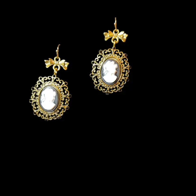 Victorian-style cameo drop earrings featuring gold-toned filigree settings with bow accents.
