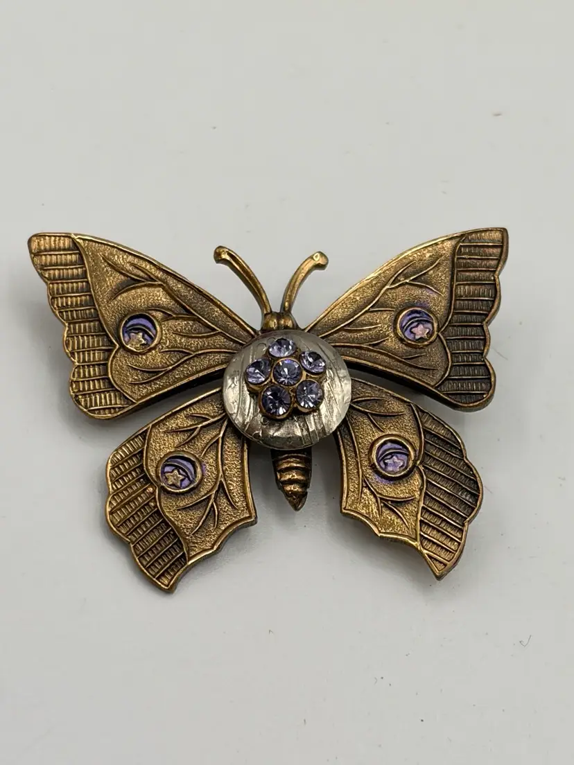 Vintage Art Deco style butterfly brooch features a yellow gold-tone finish and purple rhinestone detailing