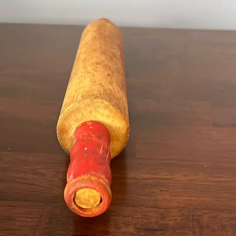 Vintage wooden rolling pin with red painted handles.