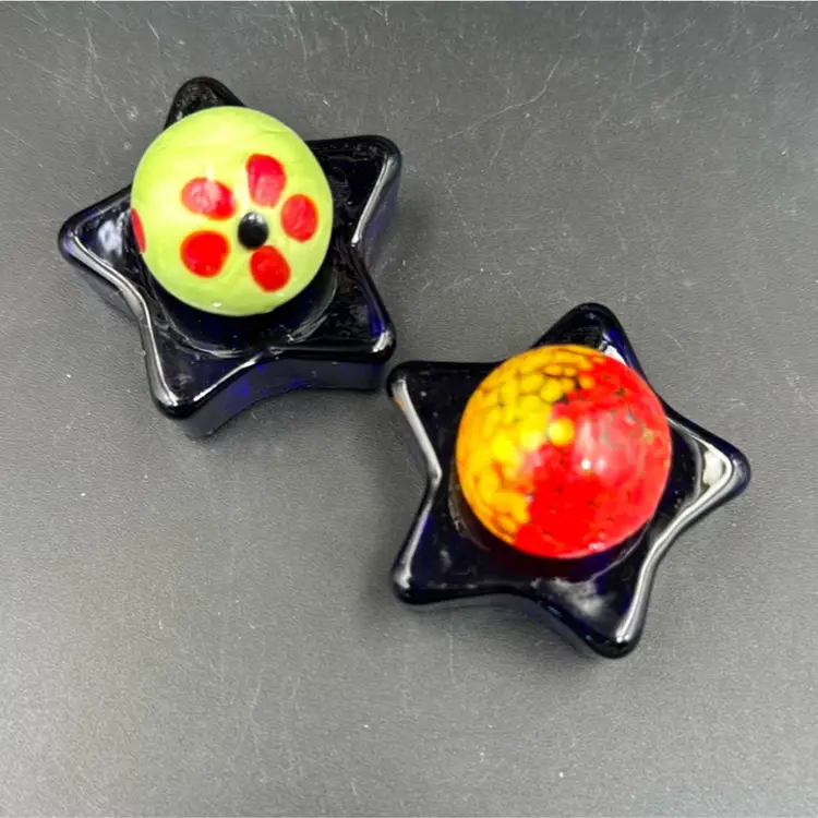 A Set Of Two Marbles, One With Floral One With Orange And Yellow, And A Set Of Stars Royal Blue Glass.