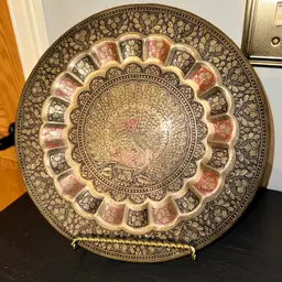 Vintage decorative brass plate with a peacock design.