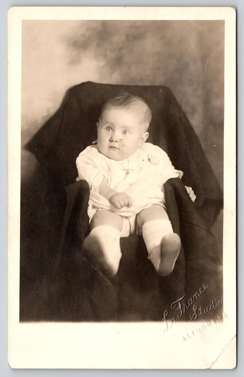 Postcard RPPC Wide-Eyed Baby in White Dress Sitting in Chair Real Photo - 8751