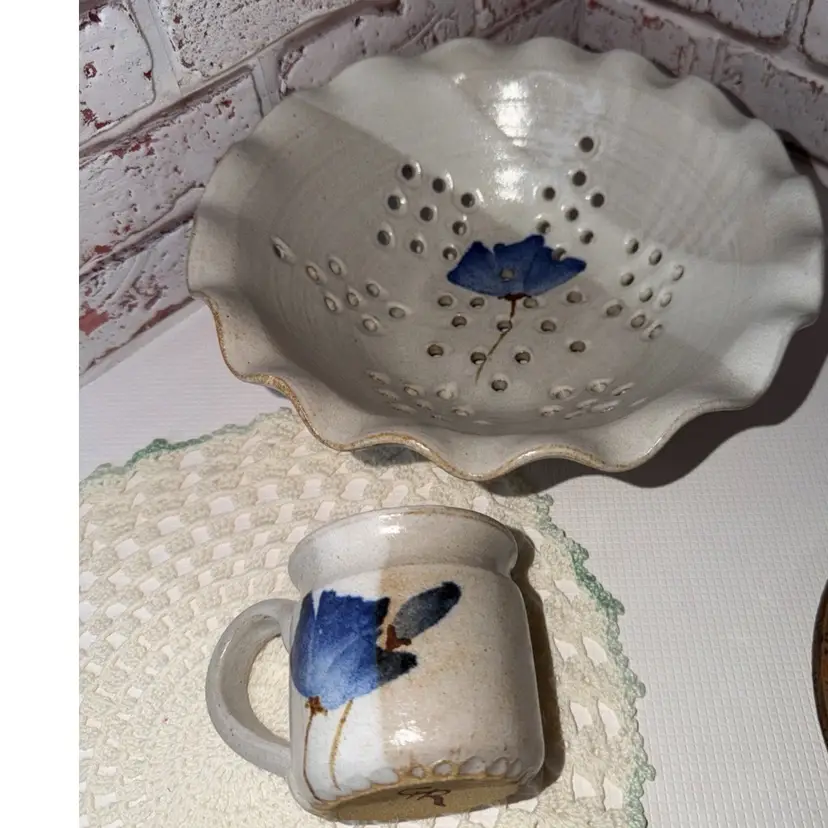 handmade ceramic berry colander bowl with a ruffled rim and a blue floral design.