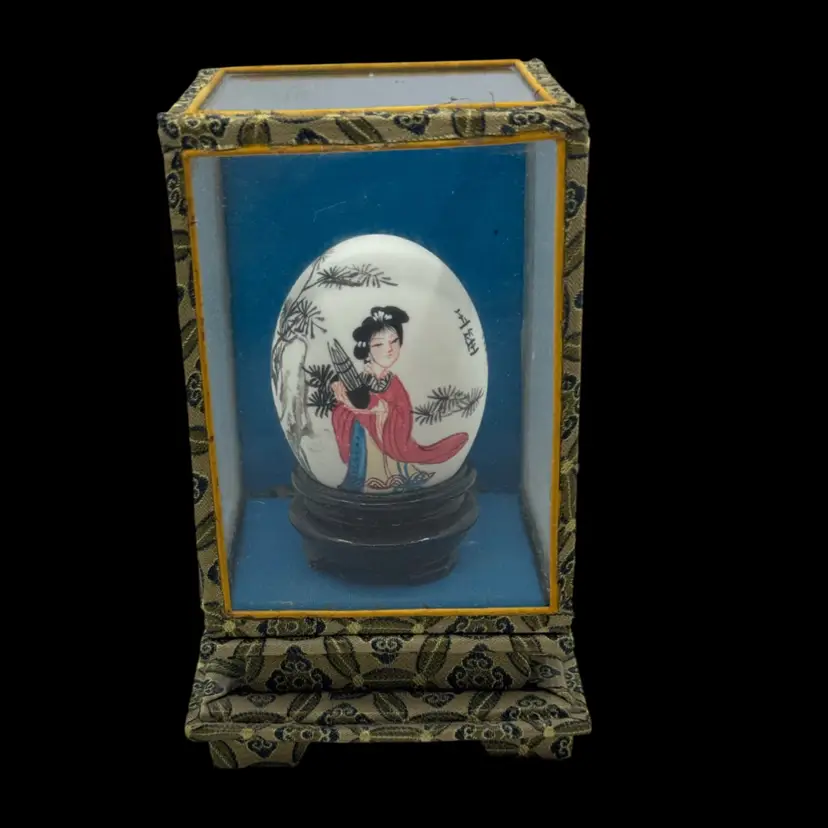Vintage hand-painted decorative egg in a glass and fabric display case.