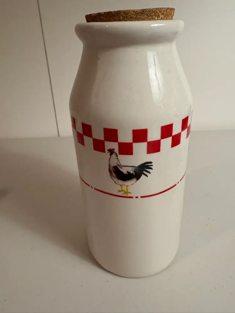 Ceramic milk jug or bottle with a rooster design and a red checkered pattern.