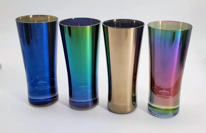 This set of The Bombay Company's "Titanium" iridescent aperitif or shot glasses are uniquely flared glasses which boast a multicolored pattern that beautifully reflects light, adding a fantastic visual effect to your bar ware. 

Each piece has a generous 2 oz capacity, perfect for your favorite apero!   They stand at a height of 3.75 inches. 

Handmade and sourced from Slovakia, these glasses from the early 2000s are not just glasses, but conversation starters. To maintain their luster, hand wash care is recommended.

They are in very good condition, there are no chips or cracks and there is almost no wear.  There is one spot on one glass where the glue from a sticker has marred the glaze.  There is also a scratch on the gold glass that you see when looking through the glass from the inside. It measures about 1 cm.  Please see pictures  for detail.

Overall, really cool looking glasses!