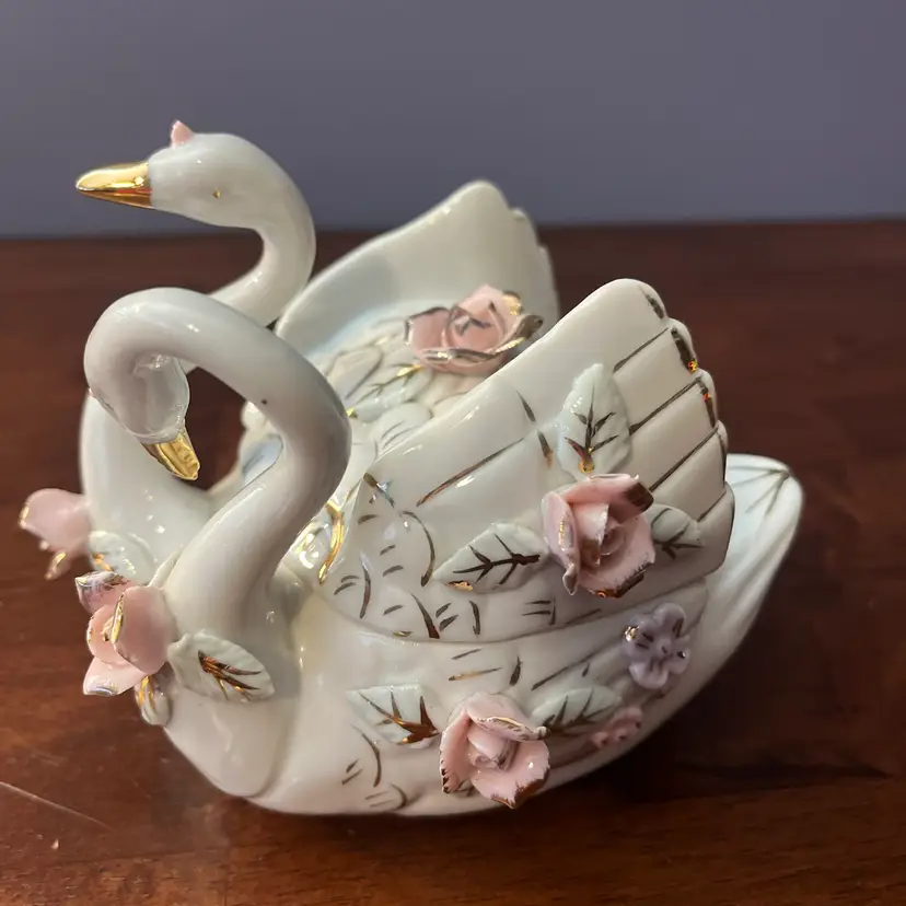 A vintage porcelain double swan trinket box with applied roses and gold trim.