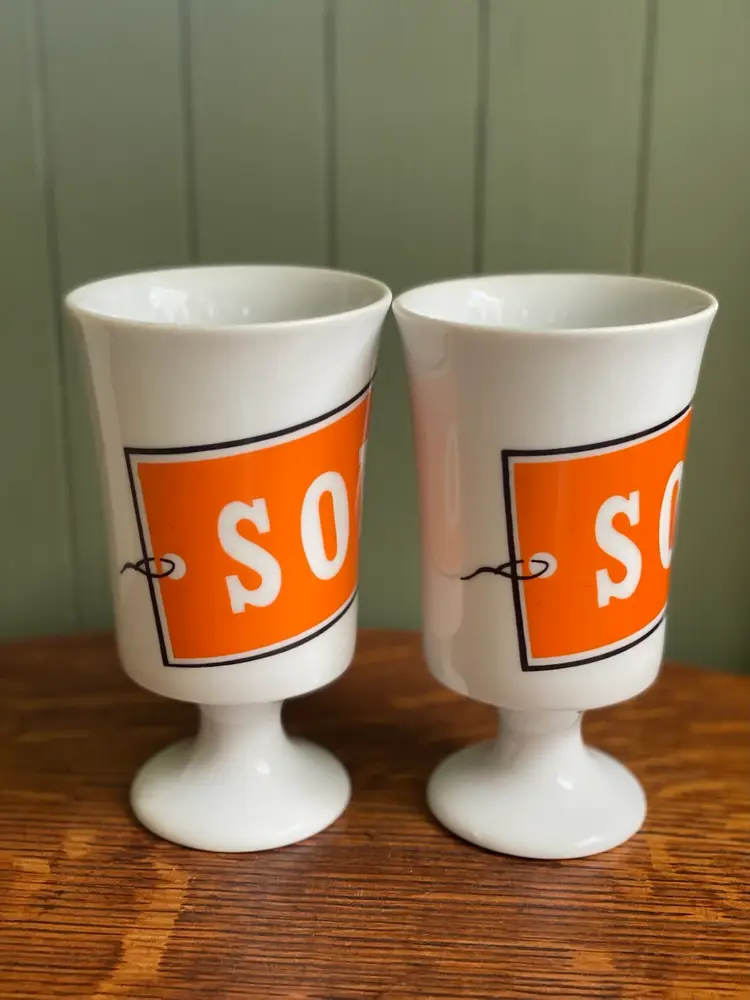 Pair Of Vintage White Pedestal Mann Made Mugs With Orange SOLD Tag On Them