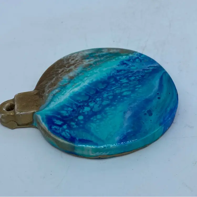 Handmade round resin Hanging Ornament with a blue and brown marbled design.