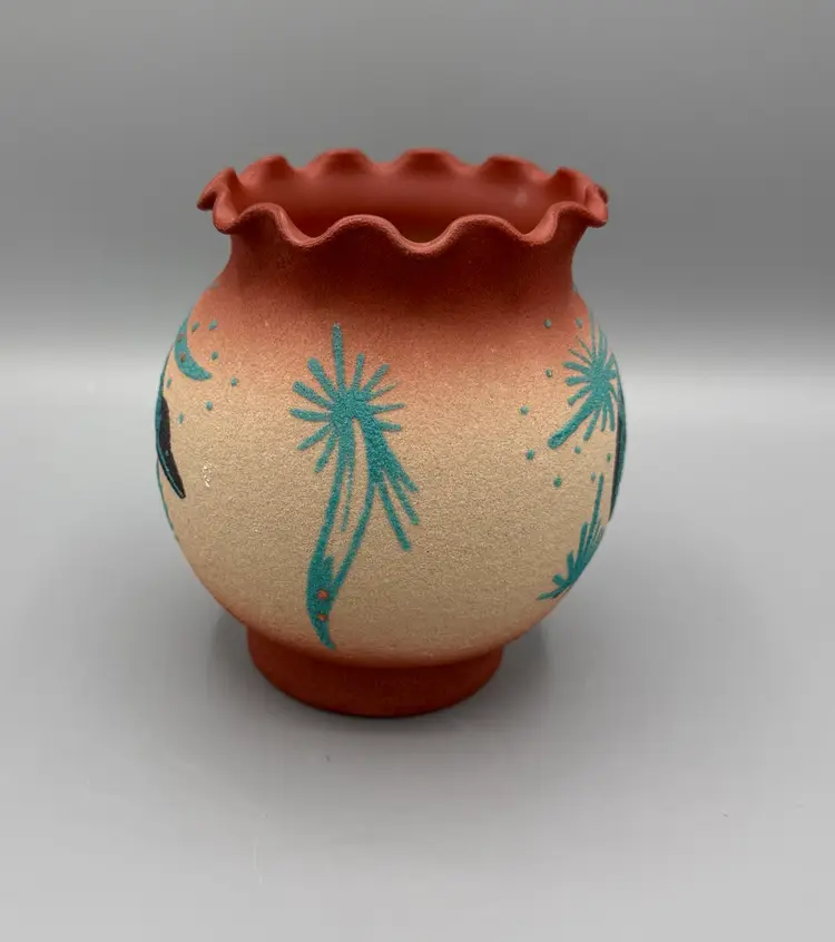 A signed, Native American sand art vase with ruffled rim and bear motif.