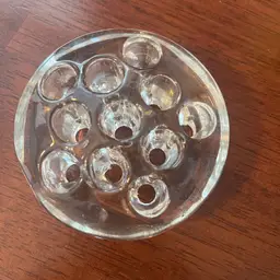 A vintage clear glass flower frog with multiple circular openings. 3.25”