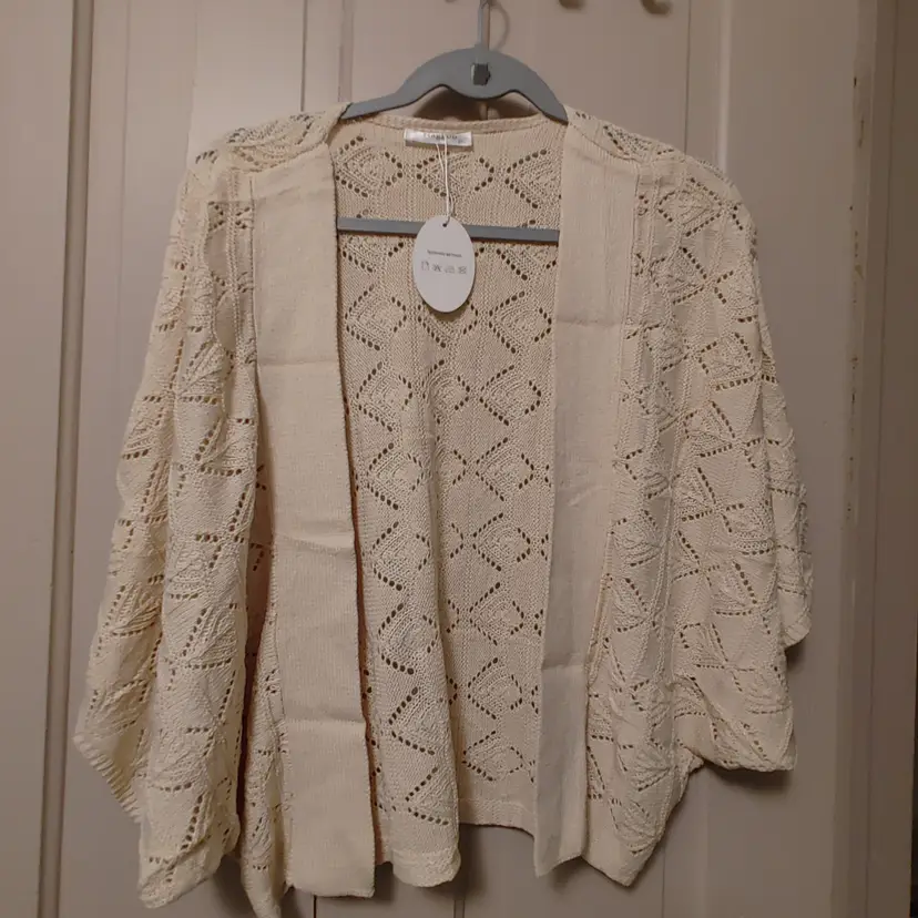 Top- Brand: Naggou. Size 2X. Cream cardigan. NWT. Material- 100% acrylic. No callouts.