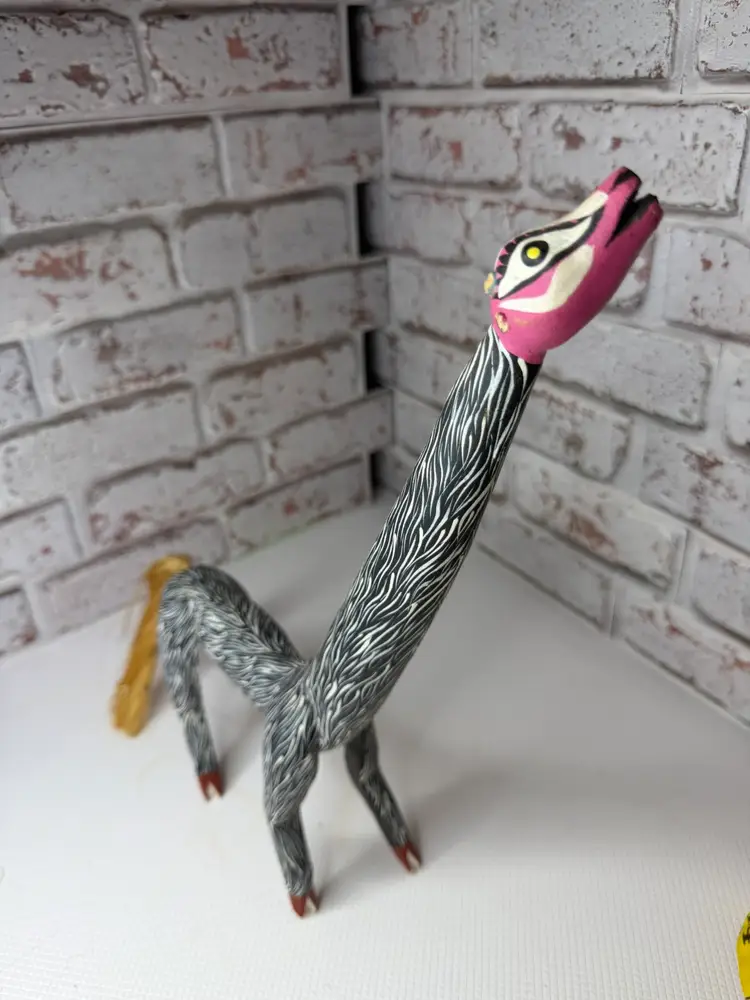 carved wooden figurine, likely a giraffe, in the style of a Mexican folk art alebrije.