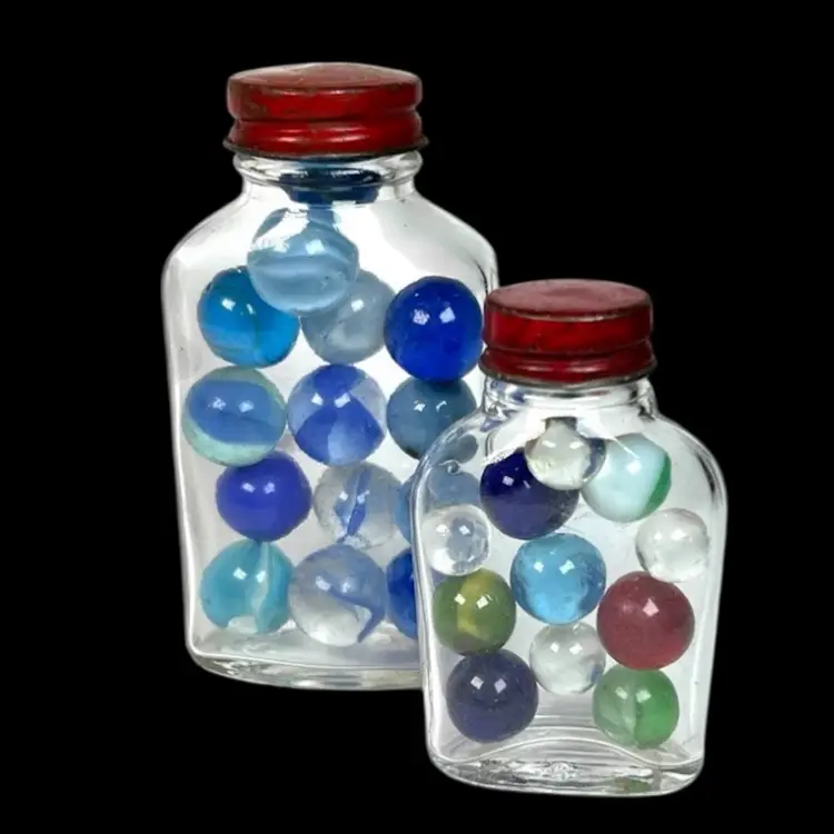 Two Vintage Jars Of Marbles.  Red Metal Lids- One Lid Says “A Genuine Bleecker Product”. Small Jar- 11 Assorted Color Marbles; Big Jar- 14 Blue Marbles.
