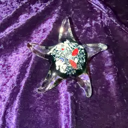 Murano-style art glass starfish paperweight, featuring a clear body with an internal millefiori design. Approximately 5.5” Wide