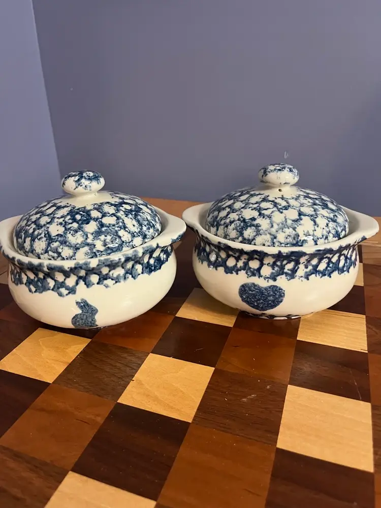 Two Tienshan Sponge Blue individual casseroles with lids, featuring folk art motifs. One Features A Cow The Other A Bunny, Both Have Hearts.
5” Diameter - 4” High With lid