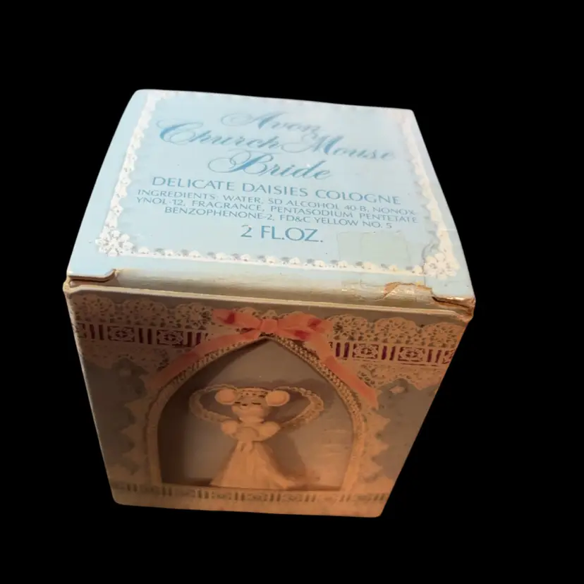 This is a vintage 1970s Avon "Church Mouse Bride" cologne decanter, featuring a mouse figure holding daisies.The 2 fl oz bottle comes in its original decorated box, often containing "Delicate Daisies" scented cologne. This Decanter Is Empty, Does Not Contain Any Fragrance.