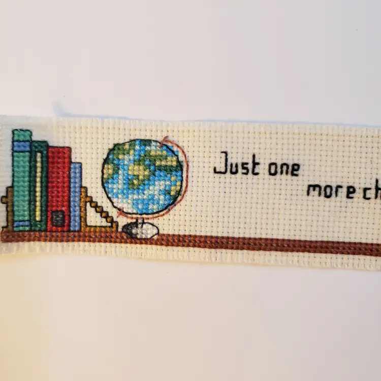 New Cross-stitched bookmark "Just One More Chapter"  on ivory Aida cloth.