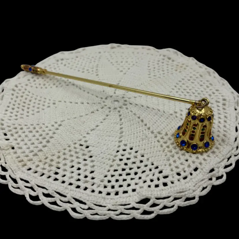 Decorative gold-tone candle snuffer with jeweled embellishments.