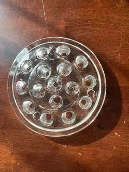 A vintage clear glass flower frog with 16 holes for floral arrangements.