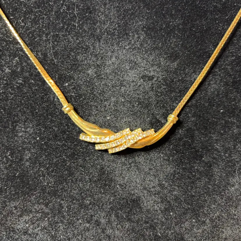 This vintage Avon gold-tone necklace features a center pendant with clear rhinestones.