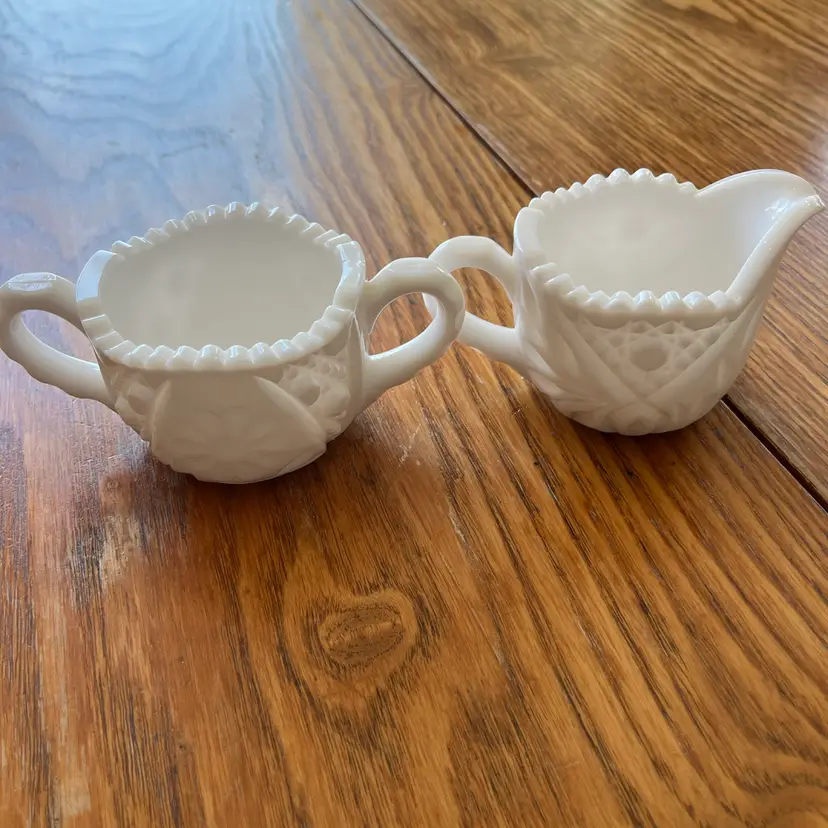 A vintage milk glass creamer and sugar bowl set with sawtooth rims.