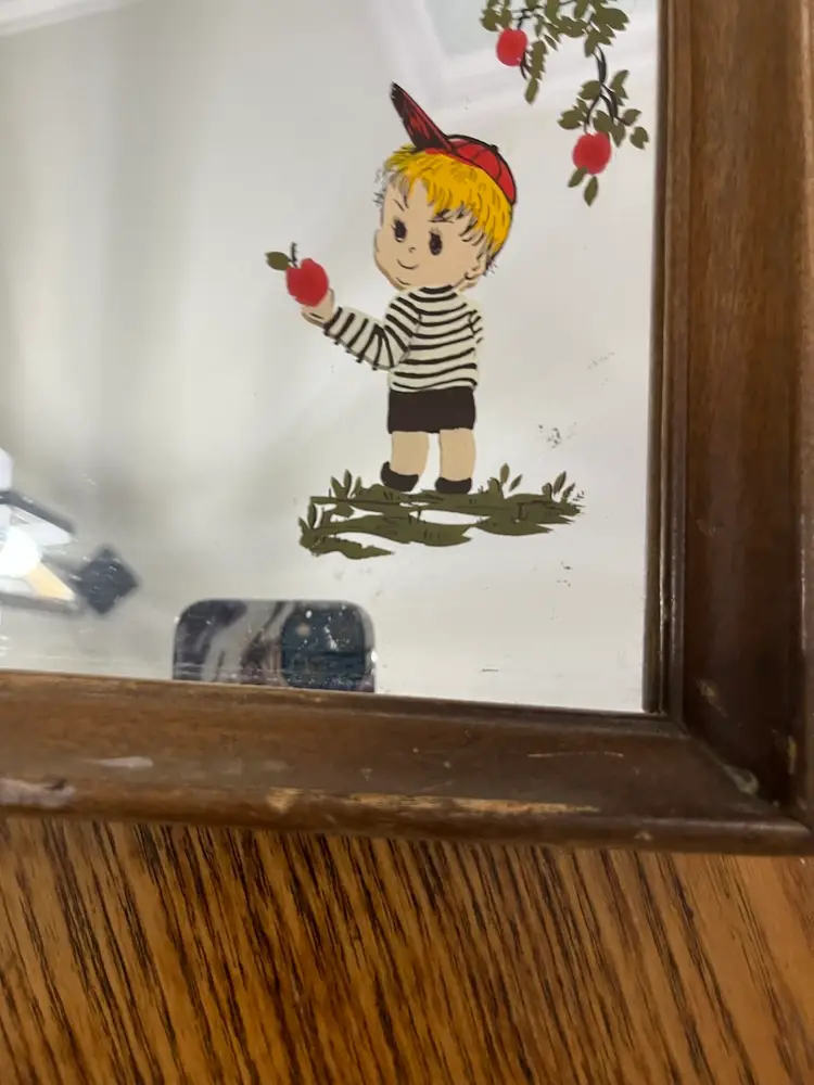 Mid-Century Modern Wooden Mirror With Hand, Painted Decoration Of Boy And Black-And-White Striped Shirt, Picking Apples.
13.5” X 10.5” 
Some WARE On Frame .
Sticker On Back, Dickinson’s Seymour, Indiana Pictures Of Distinction.