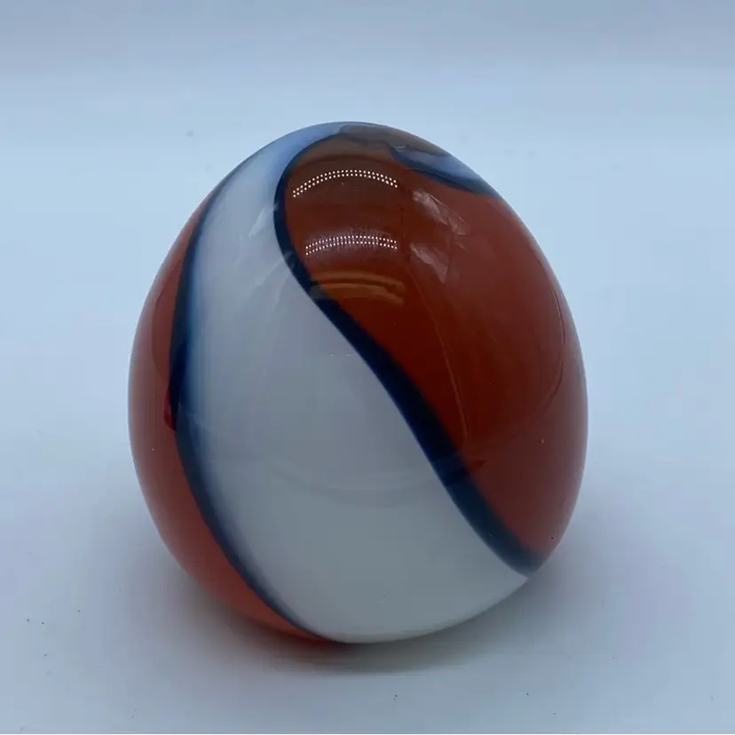 #0043 vintage American glass paperweight or marble with a swirled orange, white, and blue pattern.