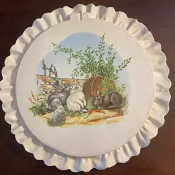 A decorative porcelain plate with a ruffled edge and rabbit illustration. - In The Shape Of An Embroidery Hoop. 12”