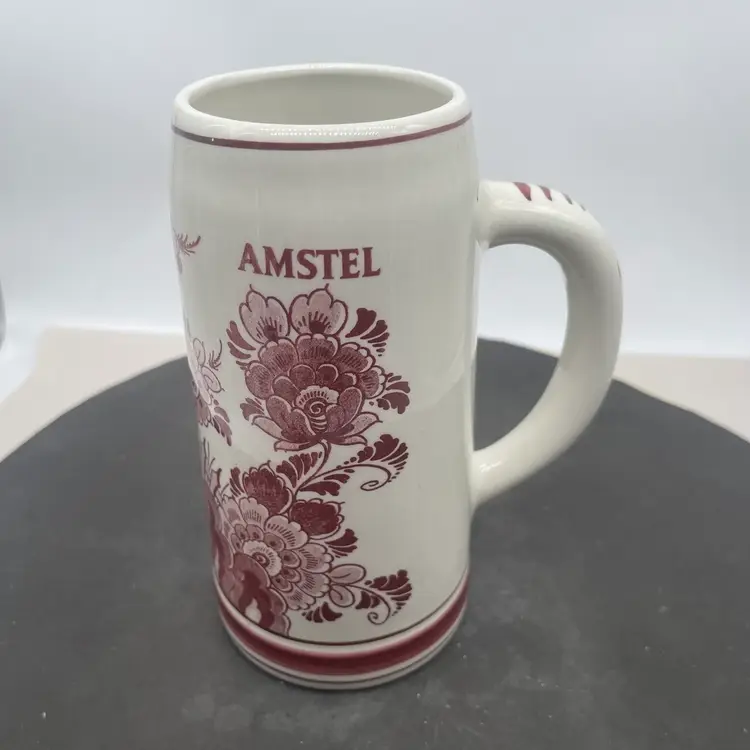#0834 vintage Amstel beer stein made in the Netherlands featuring red hand-painted designs.